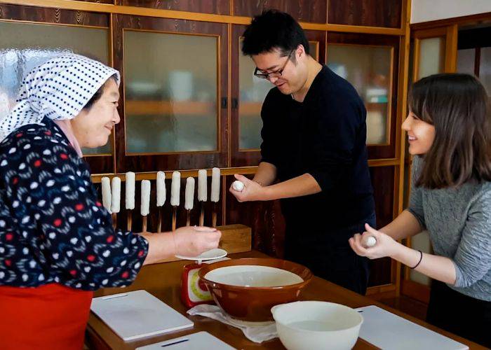 Two guests at a farm stay experience being taught how to cook Japanese food by a local.